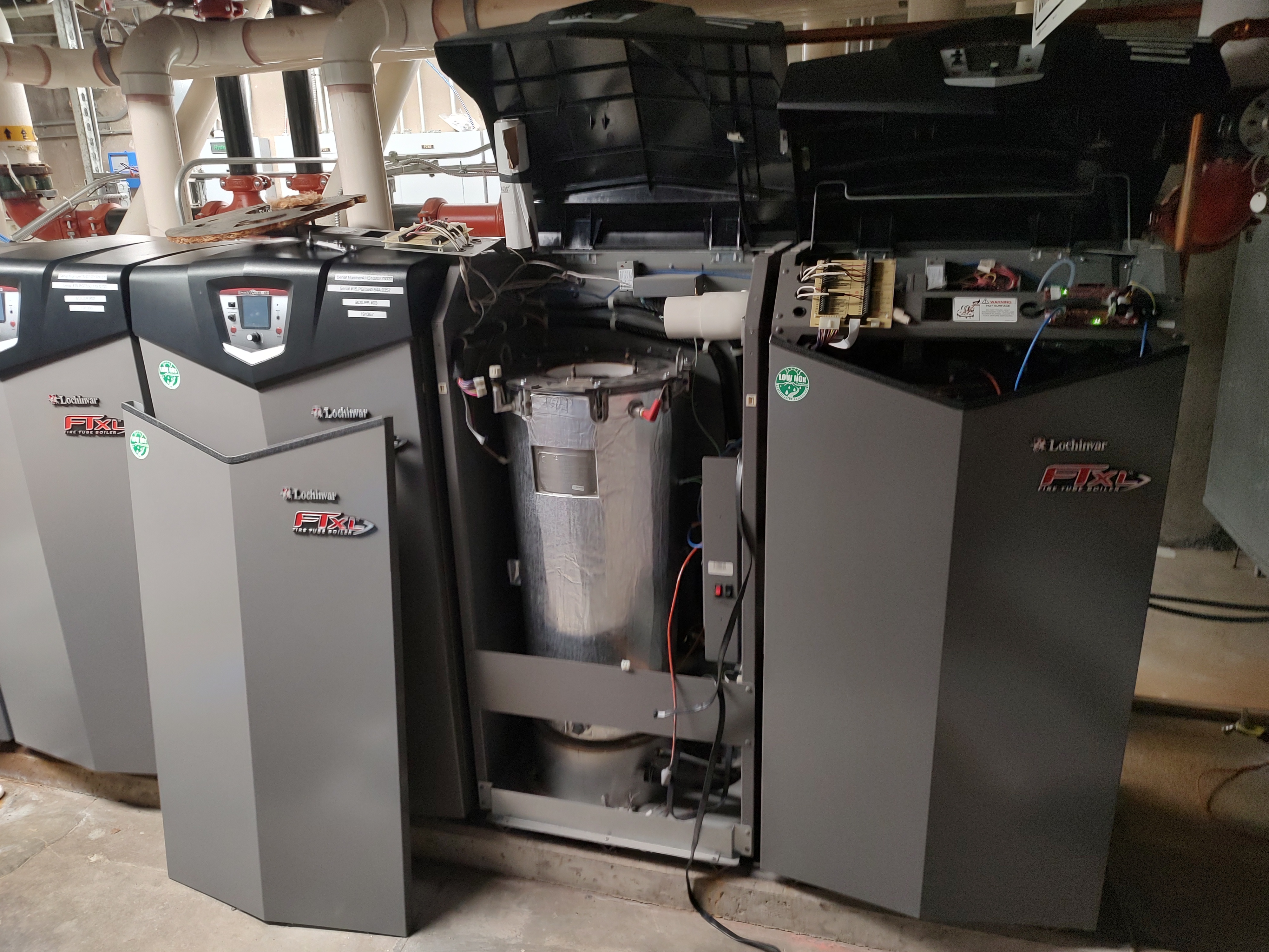 A commercial hot water tank in a basement with its cover opened for maintenance